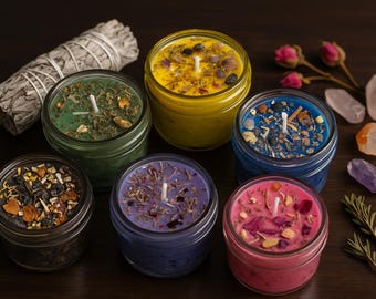 May include: An assortment of jar candles in various colors, including green, yellow, blue, purple, and pink, each topped with herbs and crystals. A bundle of sage, crystals, and sprigs of rosemary are also present.