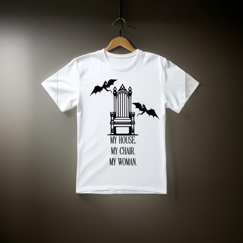 May include: White t-shirt with a black graphic of a throne with two dragons on either side. The text below the throne reads "My house. My chair. My woman."