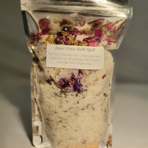 May include: A clear plastic bag filled with white bath salts, dried rose petals, and lavender. The bag has a label that reads "Inner Peace Bath Spell" and "Bath salts blended with Chamomile and Lavender oils, dried Roses, Pea Flower Lavender and Chamomile." The label also includes the text "Moon Witen Magick".