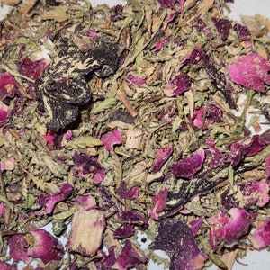 May include: A close-up of a mixture of dried herbs and rose petals. The mixture is a blend of green, brown, and pink hues.