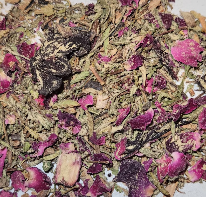 May include: A close-up of a mixture of dried herbs and rose petals. The mixture is a blend of green, brown, and pink hues.