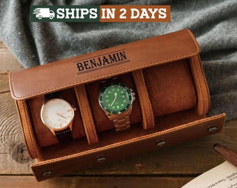 May include: A brown leather watch roll case with three interior compartments, featuring the name BENJAMIN engraved on the top flap. Two wristwatches are stored inside, one with a white face and black strap, and one with a green face and metal band.