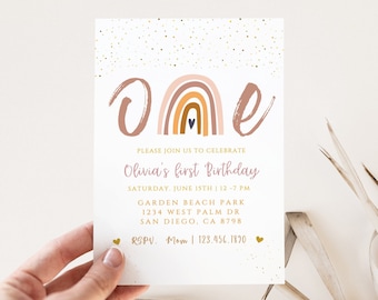 May include: A white invitation card with the word "ONE" in a brown script font, featuring a rainbow design. The card announces Olivia's first birthday, with event details in a soft pink and gold color scheme.