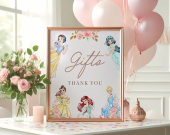 Könnte beinhalten: Ein weißes Schild mit einem roségoldenen Rahmen und einem Blumendesign. Das Schild trägt die Aufschrift "Gifts" in Kursivschrift und "Thank You" in kleinerer Schrift. Auf dem Schild sind Bilder von Disney-Prinzessinnen zu sehen, darunter Schneewittchen, Belle, Arielle und Cinderella.