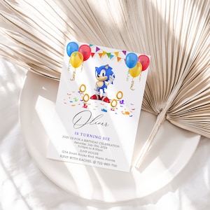 May include: A blue and white birthday invitation with a cartoon character, Sonic the Hedgehog, holding a golden ring. The invitation is decorated with colorful balloons, confetti, and the text "Oliver is turning six".