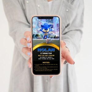 May include: A smartphone displays a birthday party invitation featuring Sonic the Hedgehog. The invitation includes the name "Nolan", date, time, and address. Additional notes are listed below the details. The phone is held by a person.