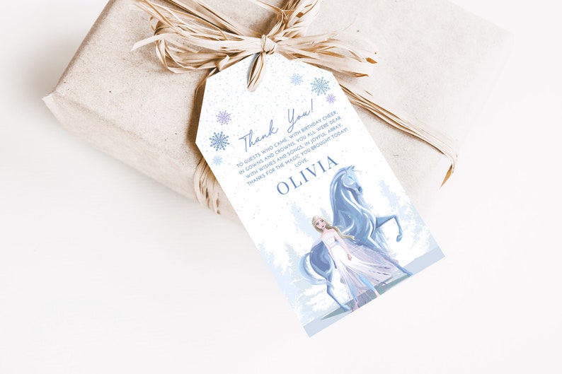 May include: A white thank you tag with a blue and white snowflake design. The tag features a cartoon image of a girl with long blonde hair wearing a blue dress and riding a white horse. The text on the tag reads "Thank You! To guests who came with birthday cheer in gowns and crowns, you all were dear with wishes and songs in joyful array. Thanks for the magic you brought today. Love, Olivia."