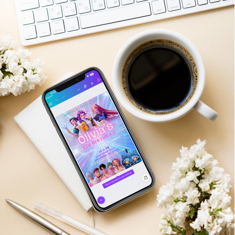以下が含まれることがあります： スマートフォンには「Olivia's 5th Birthday」と書かれた誕生日招待状が表示されています。 電話は白いメモ帳の上にあり、コーヒーカップ、ペン、白い花の隣にあります。 背景にはキーボードがあります。