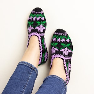 Może przedstawiać: Para czarnych, zielonych i fioletowych wełnianych skarpet-kapci z kwiatowym wzorem.