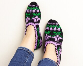 May include: A pair of black, green, and purple knitted slipper socks with a floral pattern.