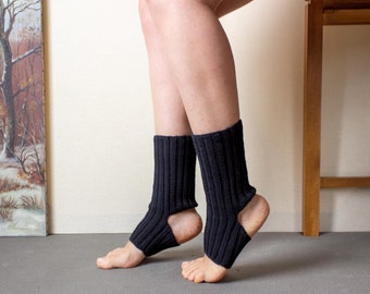 May include: A pair of black knitted ankle warmers with an open heel design. The warmers are ribbed and have a soft, cosy texture.