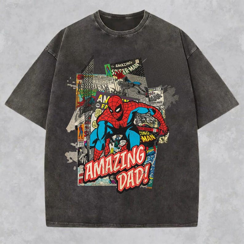 May include: Dark gray t-shirt featuring a comic book style graphic of Spider-Man in red and blue, with the text "AMAZING DAD!". The shirt has a vintage, washed look.