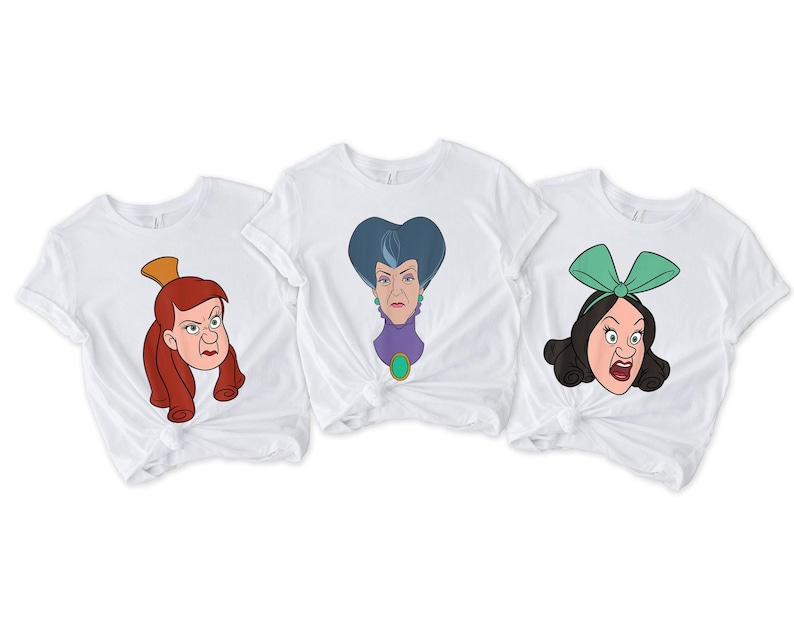May include: Three white t-shirts featuring cartoon illustrations of female characters with angry expressions. The characters have red, blue, and black hair, and are wearing accessories like a gold crown and a green bow.