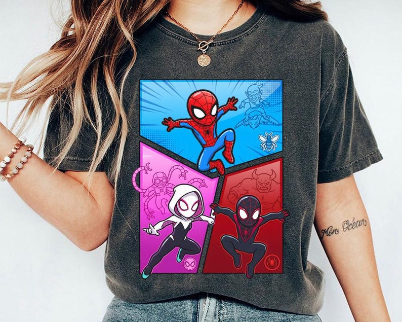 May include: Dark gray t-shirt featuring a colorful comic-style graphic of Spider-Man and other characters. The design includes Spider-Man in a blue and red suit, and other characters in a comic book style.