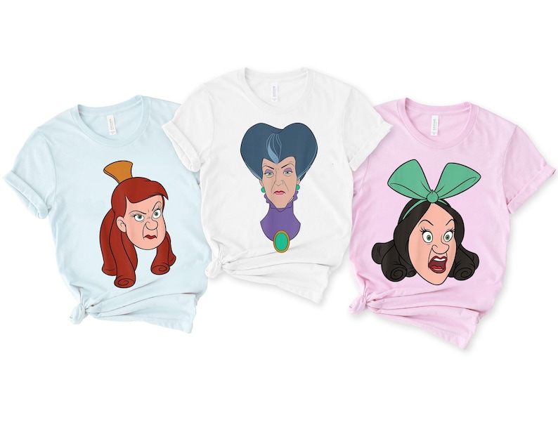 May include: Three t-shirts featuring cartoon illustrations of Cinderella's stepmother and stepsisters. The shirts are light blue, white, and pink. Each shirt has a different character illustration. The illustrations are in a cartoon style with bold outlines and bright colors.