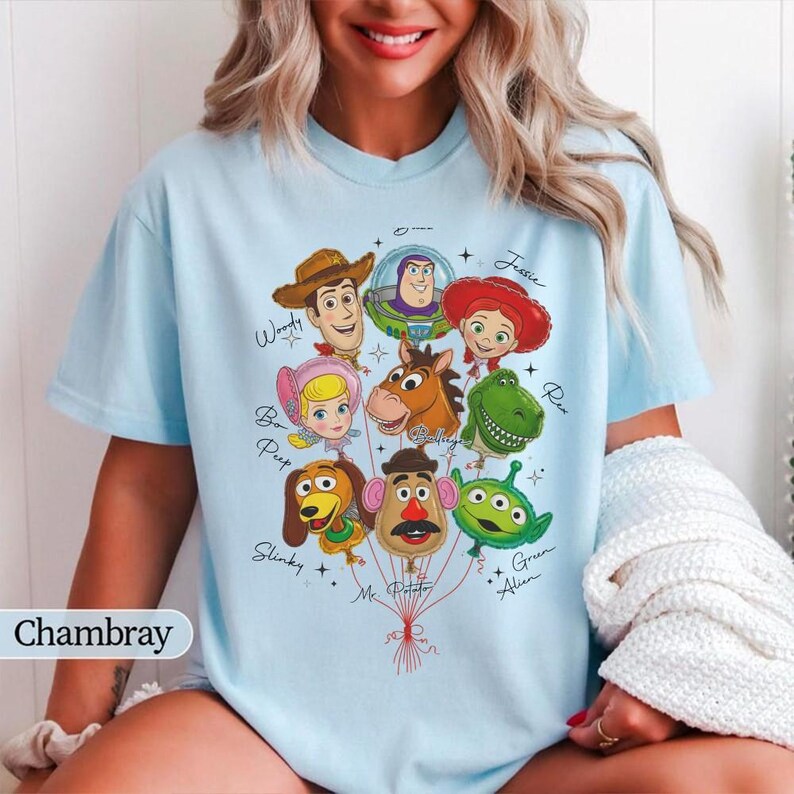 Puede incluir: Camiseta azul claro con un gr&aacute;fico de personajes de Toy Story como globos. El dise&ntilde;o incluye a Woody, Buzz Lightyear, Jessie, Bo Peep, Rex, Slinky, Mr. Potato Head y un Alien verde. La palabra "Chambray" est&aacute; en la esquina inferior izquierda.
