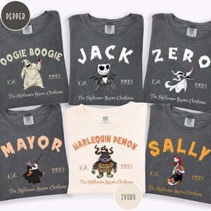 May include: Six t-shirts featuring characters from The Nightmare Before Christmas. Five shirts are dark gray with white or orange text and graphics of Oogie Boogie, Jack, Zero, Mayor, and Sally. One center shirt is ivory with the Harlequin Demon.