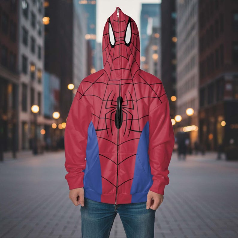 May include: Red and blue Spider-Man zip-up hoodie with a hood featuring white eye shapes. The front of the hoodie has a black spider graphic and a web design. The hoodie is worn with blue jeans.