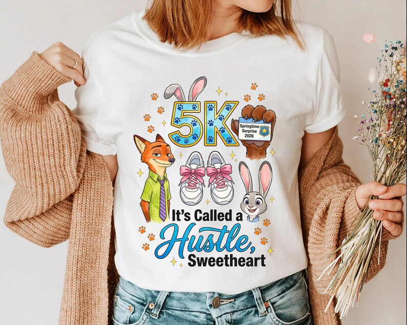 May include: White t-shirt with a Zootopia-themed design. It features the text "5K" and "It's Called a Hustle, Sweetheart", alongside cartoon characters, running shoes, paw prints, and a Springtime Surprise 2020 badge.