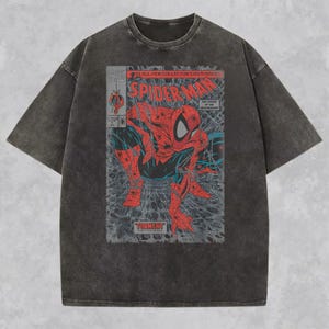 Pode incluir: Uma t-shirt de manga curta cinzento-carv&atilde;o com efeito de lavagem &aacute;cida, apresentando uma estampa gr&aacute;fica de uma capa de banda desenhada do Spider-Man. A estampa mostra a personagem vermelha e azul agachada com o texto Spider-Man e Torment.