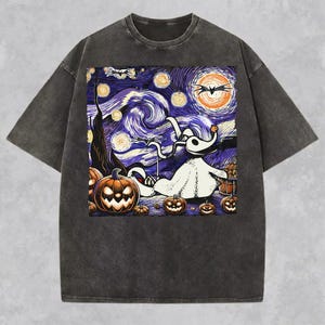 May include: A charcoal grey short-sleeve t-shirt featuring a graphic print of a white ghost dog character in a swirling, starry night sky. The design includes orange jack-o'-lantern pumpkins, bats, and a large orange moon, mimicking a classic painting style.