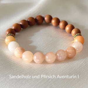 Könnte beinhalten: Armband mit hellbraunen Holzperlen und pfirsichfarbenen Edelsteinperlen. Das Armband wird durch goldfarbene Abstandshalter akzentuiert. Der Text "Sandelholz und Pfirsich Aventurin I" ist unten zu sehen.