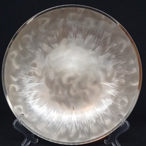 Op de afbeelding: Een zilveren serveerschaal met een decoratief geëtst ontwerp. De schaal is rond en heeft een licht verhoogde rand.