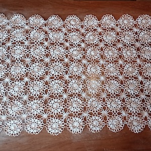 Può includere: Tovaglia all'uncinetto bianca con un delicato motivo floreale. La tovaglia ha un bordo a festoni ed è realizzata con filo sottile.
