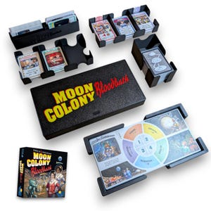 Può includere: Un set da gioco da tavolo Moon Colony Bloodbath con una scatola nera con testo giallo e rosso, diversi organizzatori di carte in plastica nera, una scatola di gioco quadrata e una plancia giocatore con un diagramma circolare.