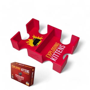 Peut inclure: Porte-cartes en plastique rouge pour le jeu de cartes Exploding Kittens. Le porte-cartes a quatre emplacements pour les cartes et présente le logo du jeu et un chat noir avec une flamme jaune.