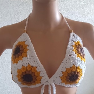 May include: White crochet halter top with sunflower designs in yellow, brown, and white.