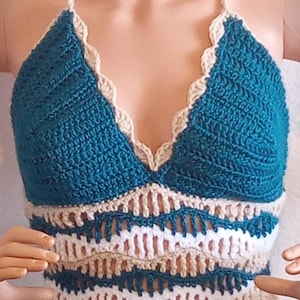 May include: Teal crochet halter top with white and beige crochet trim. The top has a scalloped edge and a v-neckline.