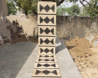 May include: A long, narrow rug with a black and white geometric pattern. The rug is made of natural fibres and has a rustic, hand-woven look.