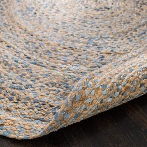 Puede incluir: Primer plano de una alfombra tejida con un esquema de color azul y beige. La alfombra está hecha de fibras naturales y tiene una superficie texturizada.