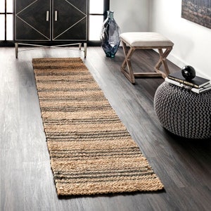 Puede incluir: Un tapete de pasillo de fibra natural con un patrón a rayas en beige y gris. La alfombra está hecha de yute y es perfecta para agregar un toque de textura natural a cualquier habitación.