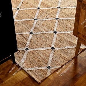 May include: A natural fiber rug with a diamond pattern in white and black. The rug is made of jute and is a natural beige color.