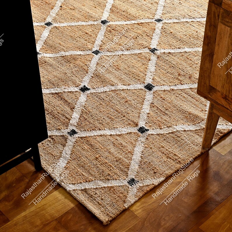 May include: A natural fiber rug with a diamond pattern in white and black. The rug is made of jute and is a natural beige color.