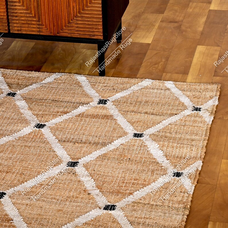 May include: A natural fiber rug with a diamond pattern in white and black. The rug is made of jute and is perfect for adding a touch of natural beauty to any room.