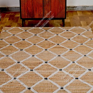 May include: A natural fiber rug with a diamond pattern in white and black. The rug is made of jute and is a natural, earthy color.