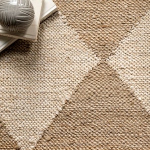 May include: A natural fibre rug with a woven pattern of light and dark brown stripes. The rug has a textured surface and a subtle ombre effect.