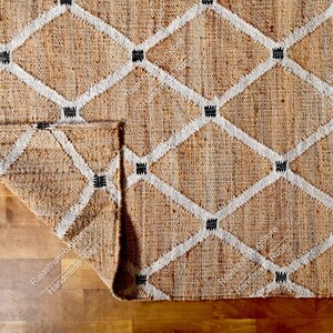 May include: A natural fiber rug with a diamond pattern in white and black. The rug is made of jute and has a natural, earthy color.