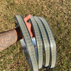 Puede incluir: Cuatro luces de cultivo LED circulares con LED blancos y cableado negro. Las luces están dispuestas en una pila y se sostienen en la mano de una persona.