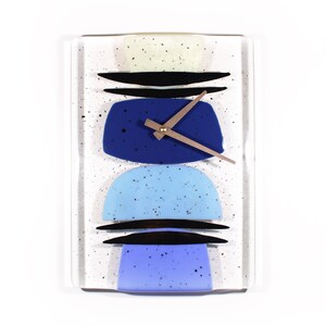 May include: A white rectangular clock with blue, light blue, and black geometric shapes. The clock hands are gold.