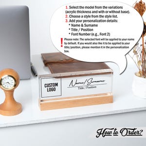 May include: A clear acrylic desk nameplate with a wooden base. The nameplate has a black and white custom logo and the text "Name/Surname" and "Title/Position". The text "How to Order?" is written in a stylized font below the nameplate.