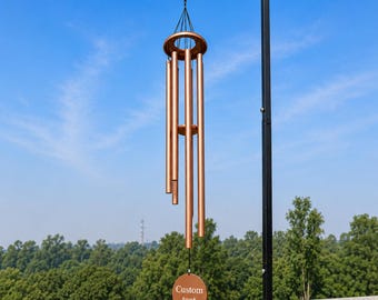 Könnte beinhalten: Ein kupferfarbenes Windspiel mit sechs zylindrischen Röhren unterschiedlicher Länge, die an einem runden Oberteil hängen. Unten hängt eine runde, flache kupferfarbene Scheibe mit dem eingravierten Text "Custom text".