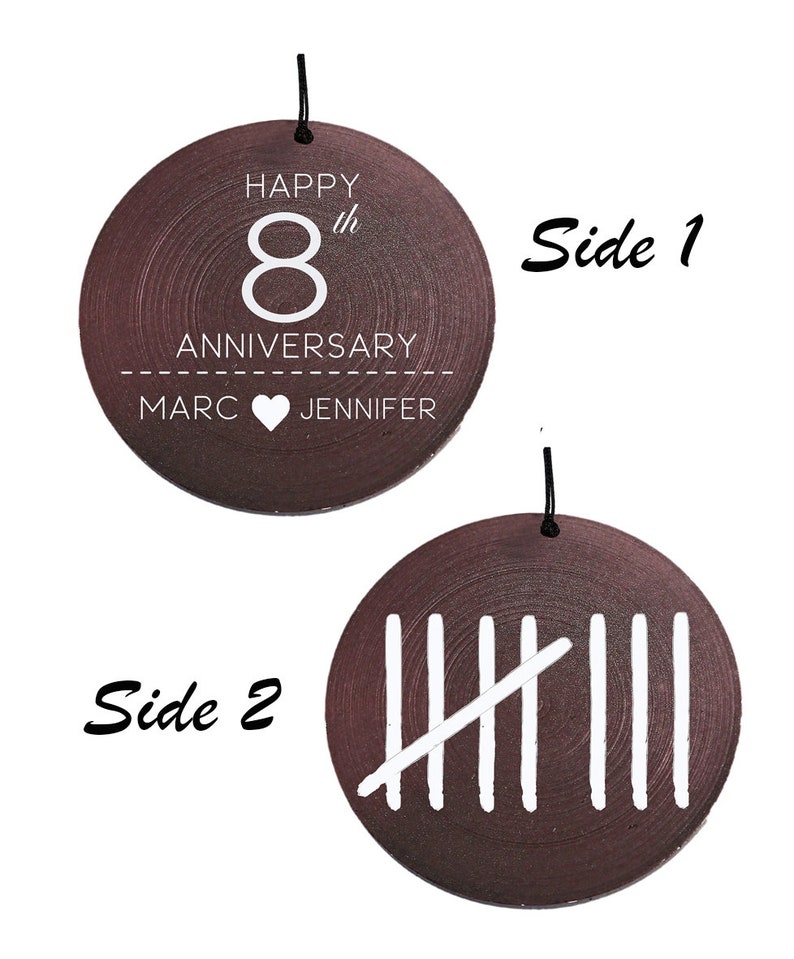 May include: A round dark brown wooden ornament with a black hanging string. Side 1 features white text reading HAPPY 8th ANNIVERSARY MARC HEART JENNIFER. Side 2 displays a white tally mark graphic representing the number eight with five vertical lines.