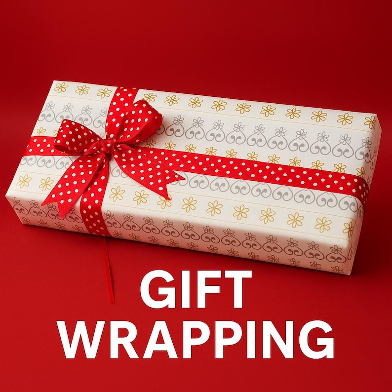 May include: A rectangular gift box wrapped in white paper with a repeating pattern of gold flowers and grey heart-shaped motifs. A bright red ribbon with white polka dots is tied in a bow around the box. The text GIFT WRAPPING is below.