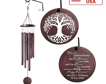 May include: A wind chime with dark metallic tubes and a circular wooden topper, accompanied by two round wooden plaques. One plaque features a white tree of life design, while the other displays the text: Never underestimate the difference you made and the lives you touched. Happy Retirement. Harold J. Williams. 30 Jun 2020.