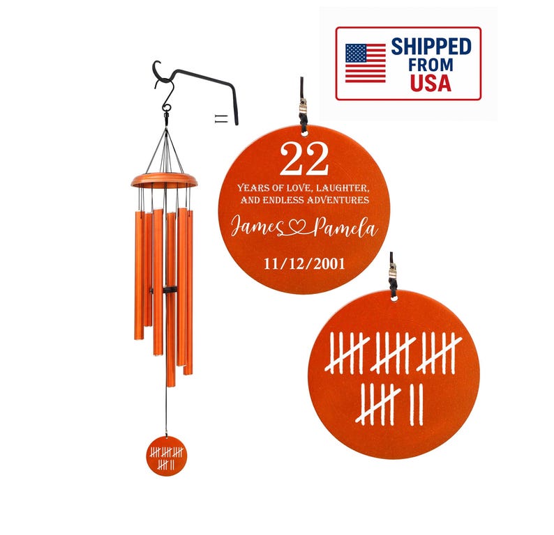 May include: Orange wind chimes with a wooden top and six orange tubes. Two orange circular ornaments display the number 22, names, and a date. The other ornament shows tally marks.