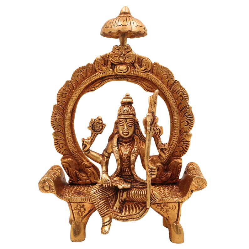 Puede incluir: Estatua de lat&oacute;n detallada de una deidad sentada en un banco, enmarcada por un arco ornamentado. La estatua sostiene una flor de loto y un bast&oacute;n, con una estructura en forma de paraguas encima. La figura est&aacute; adornada con detalles intrincados.